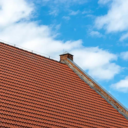 Traditional red ceramic tiles forming a textured roof surface under a bright blue sky